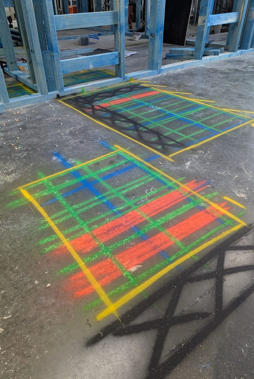 Colour-coded GPR scan grids painted on a concrete slab in front of timber wall framing