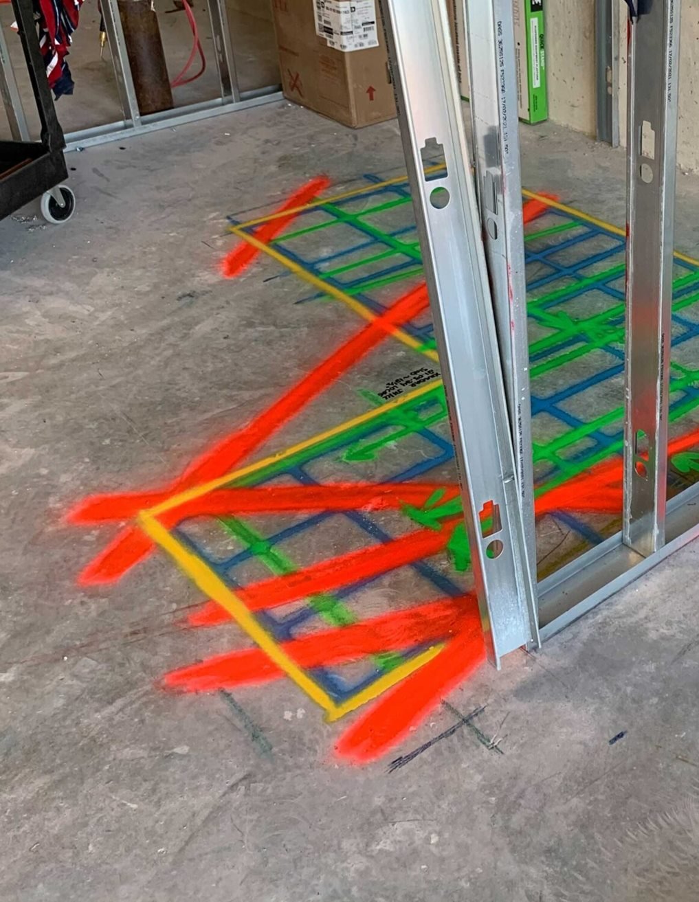 Scan grid and red lines painted on a concrete floor next to steel wall studs