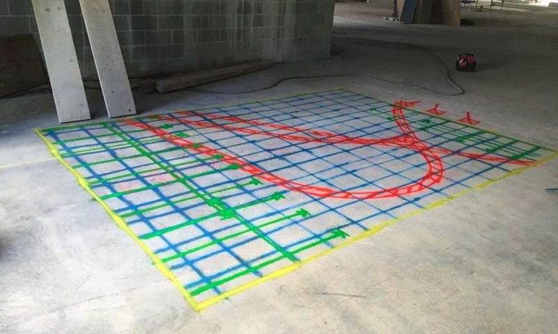 Underground utility runs marked across a concrete slab ahead of excavation